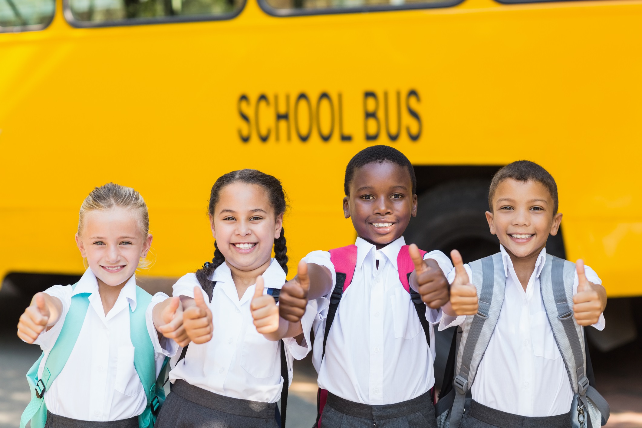 Kids with thubs up in front of bus-Wavebreakmedia Ltd